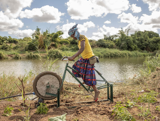 Impacto real en el terreno de proyectos de cooperación internacional. Una mujer obteniendo agua del río pedaleando una bicicleta estática.